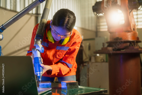 asian female engineer specialist with Measuring machine with a manipulator arm.Three-dimensional coordinate measurement. Check sizes. 3D check of the sizes of parts. CMM after machining process