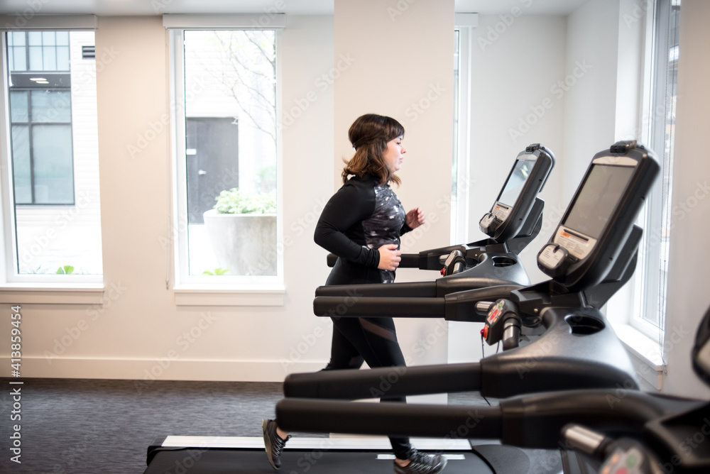 Side profile of woman running on treadmill in fitness room Side profile of woman running on treadmill in fitness room