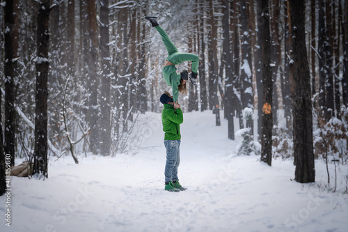 Acrobatic duo making nice pose in the snowy forest during the winter. Concept relationship, happiness and trust photo