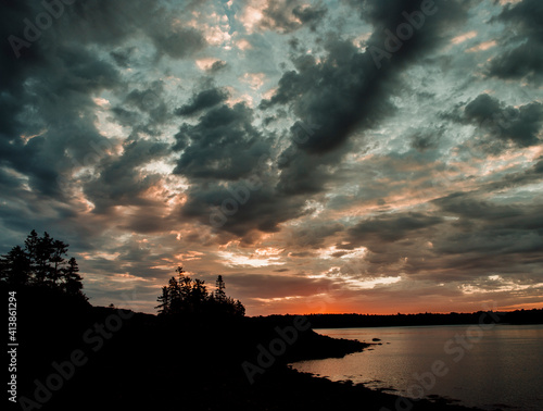 The sun rises over silhouetted trees in Cobscook Bay State Park, Maine photo