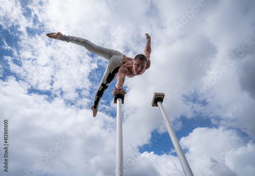 Flexible male circus Artist keep balance by one hand against amazing cloudscape. Individuality, outstanding and originality.
