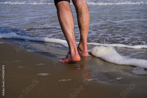 Piedi scalzi sulla spiaggia e onda che li bagna photo