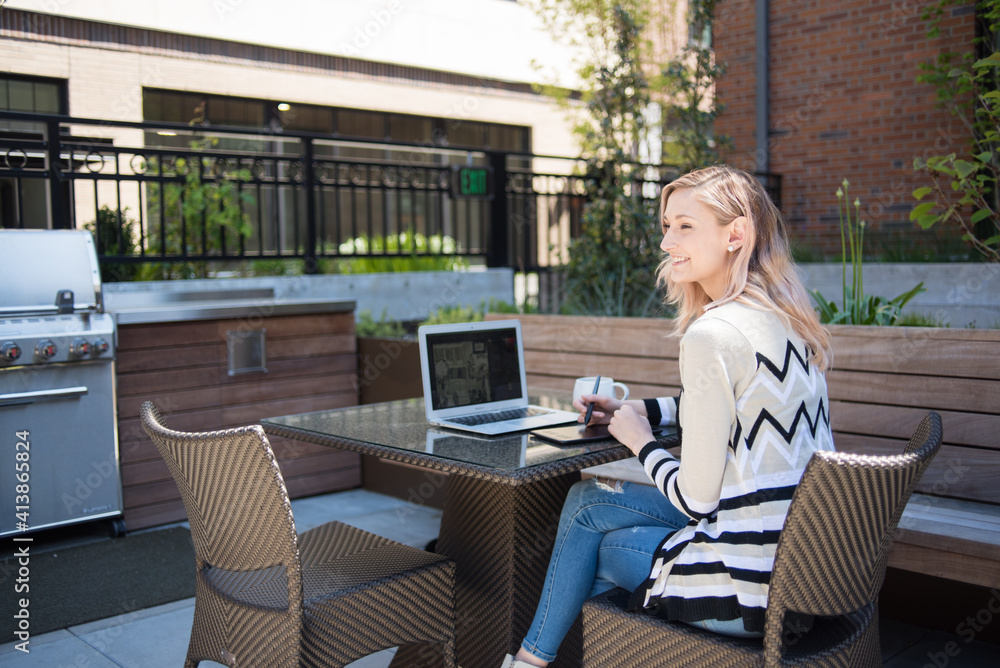 Happy woman working on computer outdoors on patio