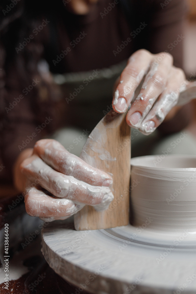 close up hand modeling pottery on a potter wheel in a cozy home workshop. Creating products from environmentally friendly clay with their own hands. Aesthetically beautiful female hands of the artist