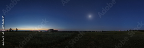 Panorama at dawn of objects in solar system in june 2020 with comet Neowise, Jupiter, Saturn, Mars, Venus and the Moon over field with old barn