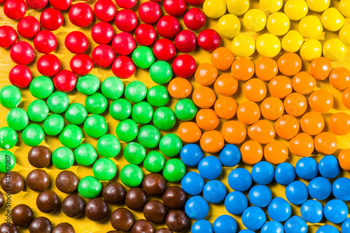 M&M's candy on the yellow background, colorful candy, multicolored gradient