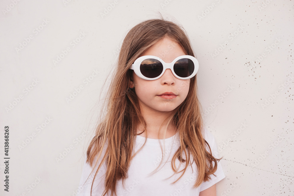 Young girl wearing sunglasses leaning against wall outside Young girl wearing sunglasses leaning against wall outside