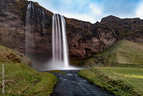 Seljalandsfoss waterfall with a great sunset on popular tourist destination, where tourists can walk behind the falling waters, part of the golden circle