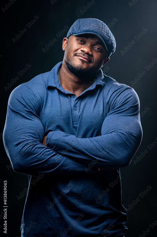 Confident smiling man holds hands crossed. Photo of african man in casual outfit on black background. Confident smiling man holds hands crossed. Photo of african man in casual outfit on black background.