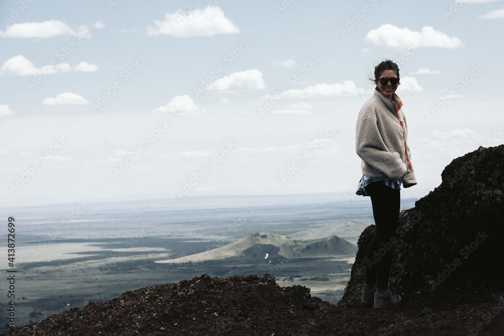 hiking woman in fleece smiles at camera on top of a distinct volcano hiking woman in fleece smiles at camera on top of a distinct volcano