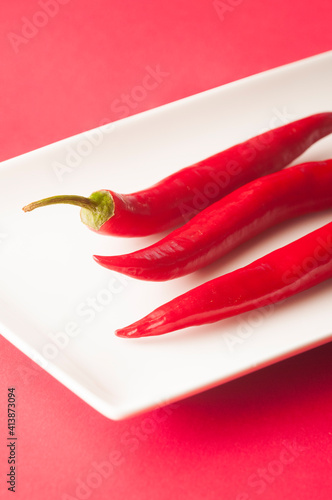 hot chili peppers  on white plate and pink background