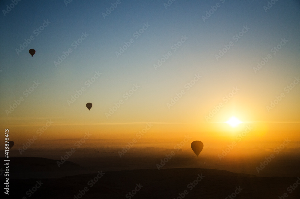 Hot air balloons fly over the Sahara desert during sunrise Hot air balloons fly over the Sahara desert during sunrise