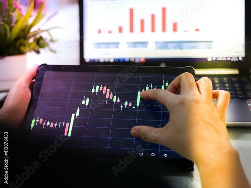 Businessman checking stock market dataมStock Market Application for Mobile, Analyzing Data Stock Market on Mobile Young Businessman with Smartphone and Stock Market Chart Background.
