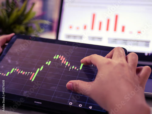 Businessman checking stock market dataมStock Market Application for Mobile, Analyzing Data Stock Market on Mobile Young Businessman with Smartphone and Stock Market Chart Background.