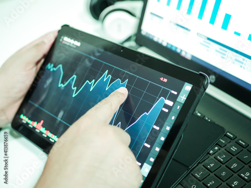 Businessman checking stock market dataมStock Market Application for Mobile, Analyzing Data Stock Market on Mobile Young Businessman with Smartphone and Stock Market Chart Background.