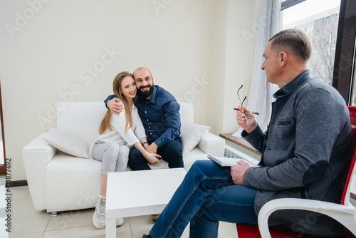 A young happy married couple of men and women talk to a psychologist at a therapy session. Psychology.