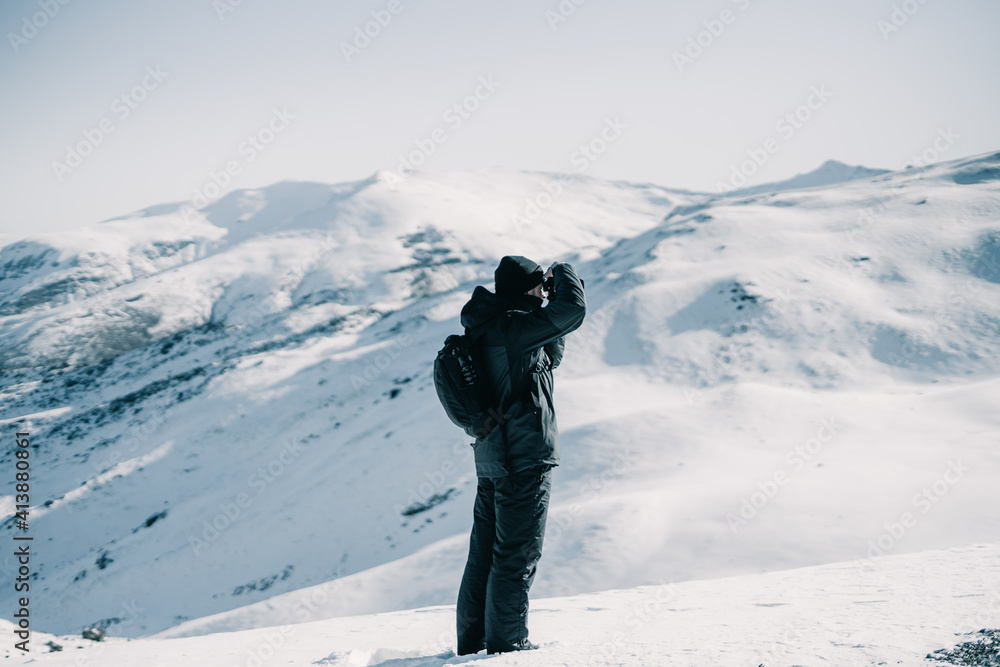 Adventure photographer taking a photo on a snowy mountain.