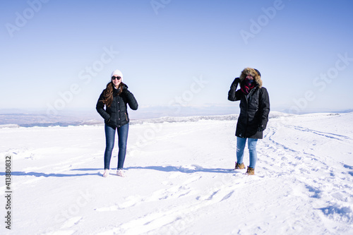 Two attractive women walking in the snow in thermal clothing.