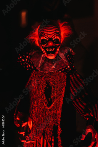 Fototapeta Closeup view of a scary clown mannequin placed in the dark room with red lights