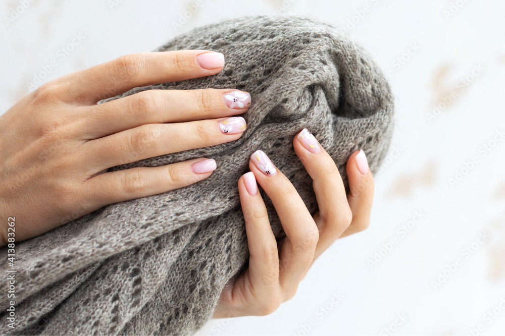 Pastel beige manicure on the light background. Manicured nails and soft hands skin. Woman's hands on warm scarf. Pastel beige manicure on the light background. Manicured nails and soft hands skin. Woman's hands on warm scarf.