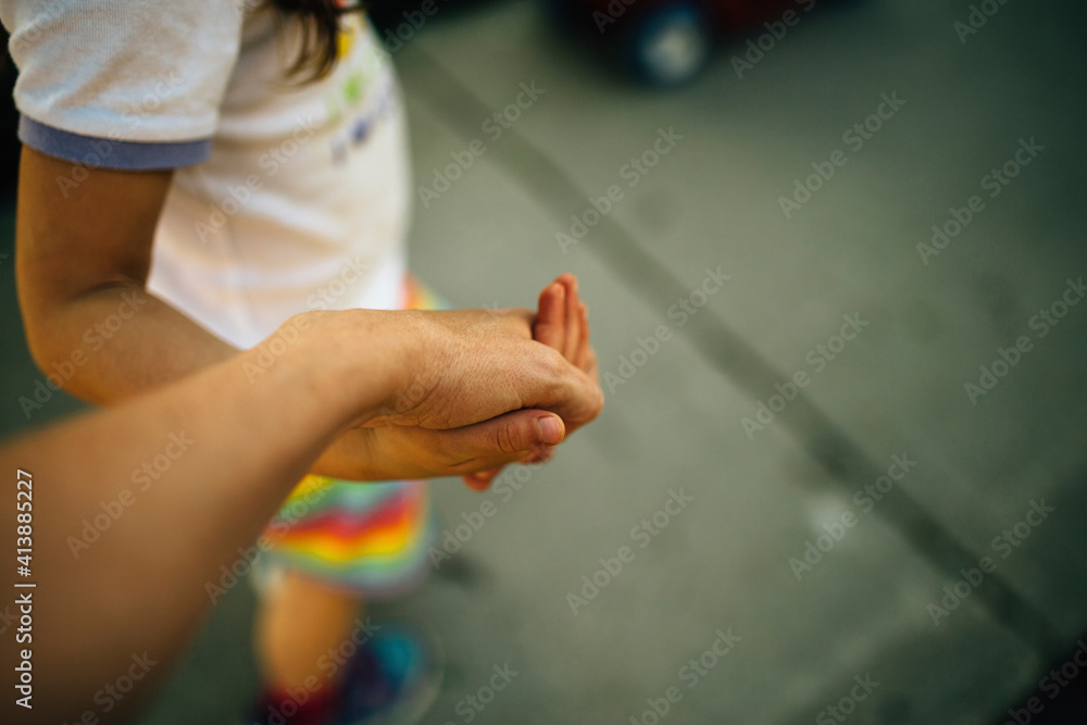 High angle view of mother and daughter holding hands while walking on footpath High angle view of mother and daughter holding hands while walking on footpath