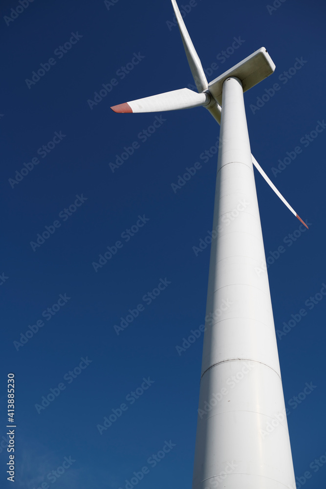 Low angle view of windmill against clear blue sky during sunny day Low angle view of windmill against clear blue sky during sunny day