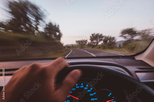 Cropped hand of man driving car on road photo