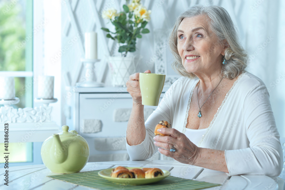 beautiful smiling senior woman drinking tea with cookies
