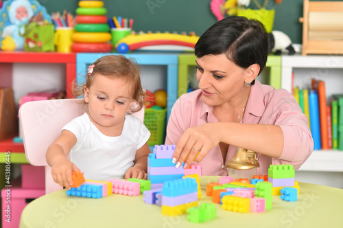 young mother and little daughter playing blocks game