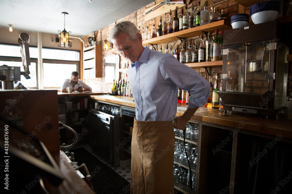 Owner wearing apron at bar counter in cafe Owner wearing apron at bar counter in cafe