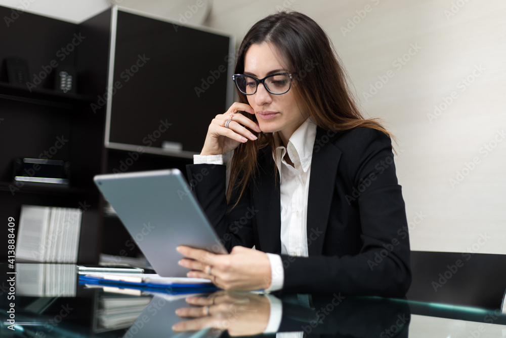 Young thoughtful secretary using a digital tablet at her desk Young thoughtful secretary using a digital tablet at her desk
