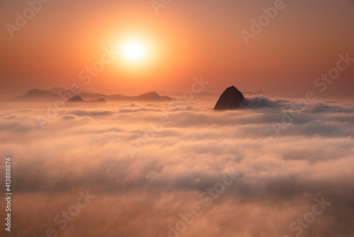 Beautiful landscape of sunrise and mountain rising above low clouds photo