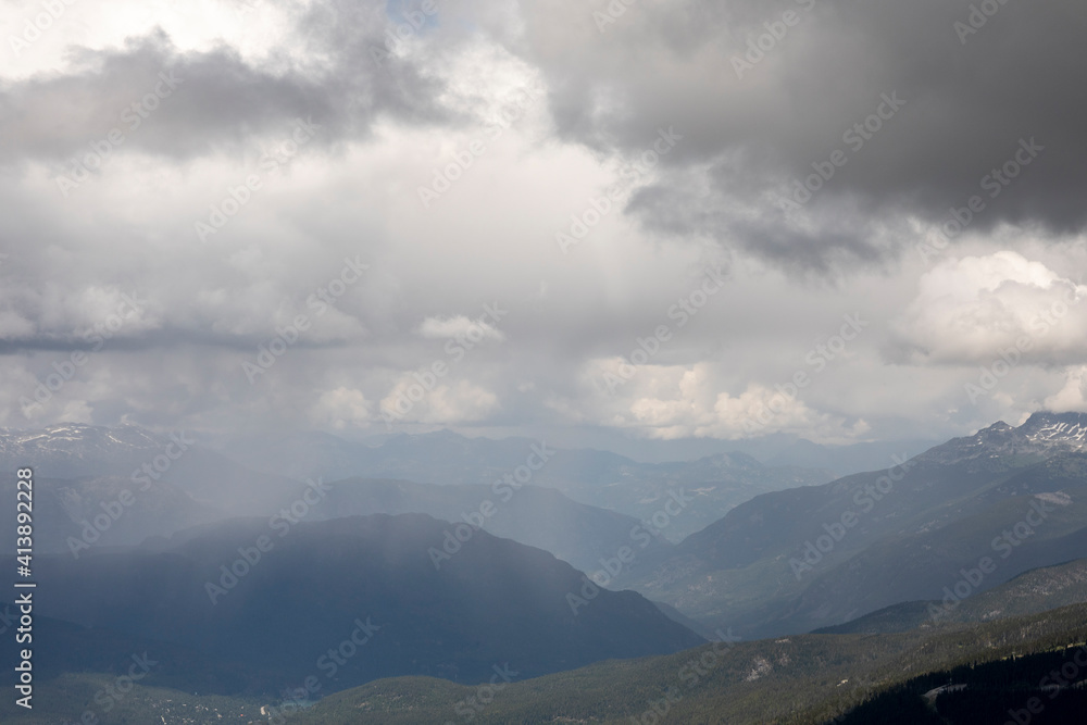 A rain storm is seen in the distance when looking at the Whistler valley from the mountain peak on a spring day. A rain storm is seen in the distance when looking at the Whistler valley from the mountain peak on a spring day.