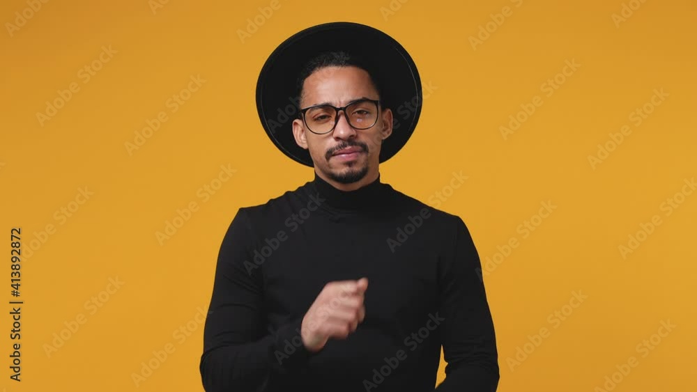 Puzzled pensive young african american man 20s in casual black clothes hat eyeglasses isolated on yellow color background in studio. People lifestyle concept. Looking aside up put hand prop up on chin Puzzled pensive young african american man 20s in casual black clothes hat eyeglasses isolated on yellow color background in studio. People lifestyle concept. Looking aside up put hand prop up on chin