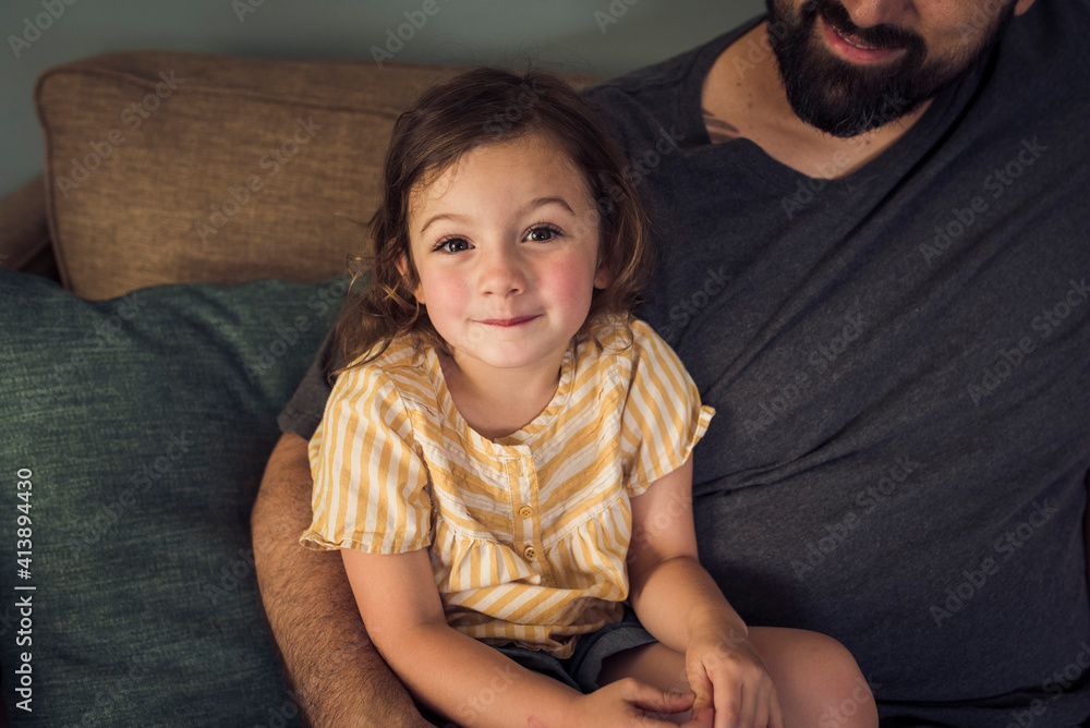 High angle portrait of girl sitting with father on sofa at home High angle portrait of girl sitting with father on sofa at home