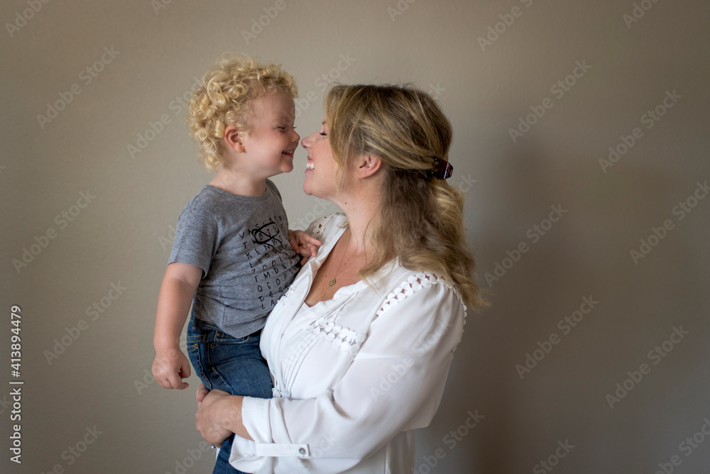 Cheerful mother carrying son against wall at home Cheerful mother carrying son against wall at home