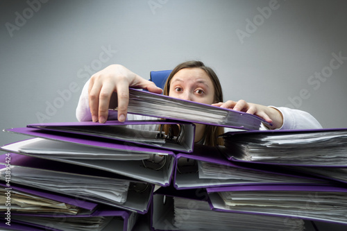 Fotografia raised hands of a person who sinks behind stacks of ring binders on an office desk