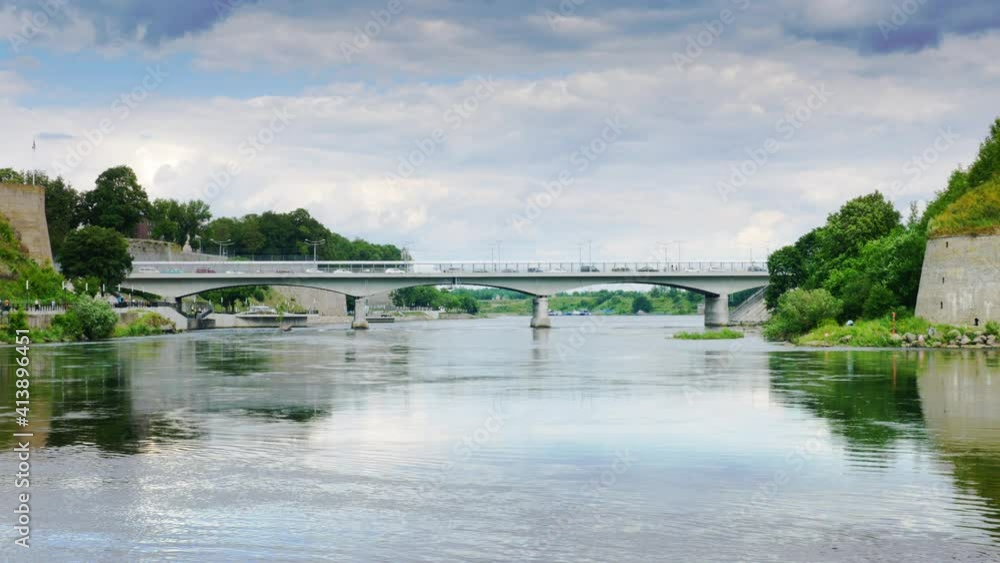 Vehicles crossing Russian Estonian border using Narva river bridge, two historic landmarks on both sides, Narva Herman castle and Ivangorod fortress, cloudy sky horizon vista Vehicles crossing Russian Estonian border using Narva river bridge, two historic landmarks on both sides, Narva Herman castle and Ivangorod fortress, cloudy sky horizon vista