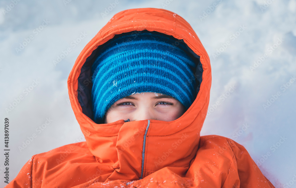 High angle portrait of boy in warm clothing lying on snow covered field High angle portrait of boy in warm clothing lying on snow covered field