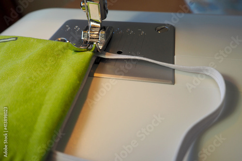 процесс пошива защитной маски на лицо зеленого цвета на швейной машинке вид сбоку