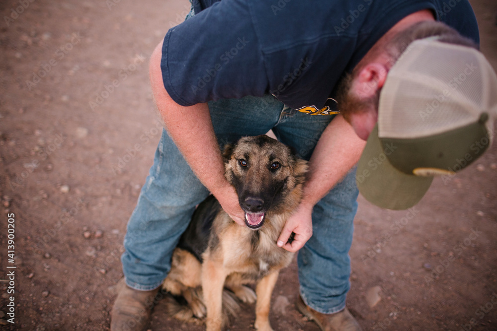 Man wearing cap while playing with dog on field Man wearing cap while playing with dog on field