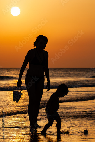silhouette of mom playing with son on the beach at sunset