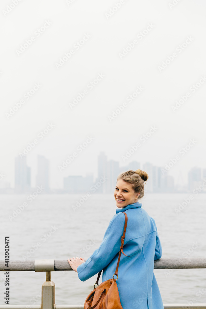 Rear view portrait of cheerful young woman standing by railing against river and clear sky in city Rear view portrait of cheerful young woman standing by railing against river and clear sky in city