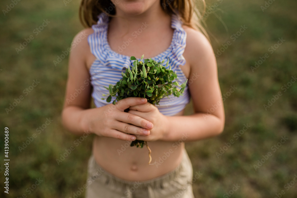 Midsection of girl holding plants while standing on field at backyard Midsection of girl holding plants while standing on field at backyard