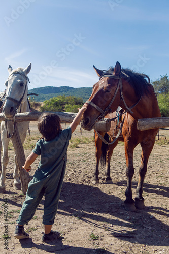 boy strokes a horse that is standing on the street in the mountains