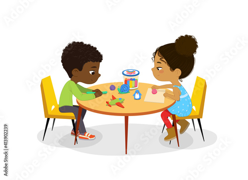African American Boy and Girl sit at the round table and sculpt clay figures. Fine motor skills development. Sculpting activity in the art class. Poster with the Place for the text.