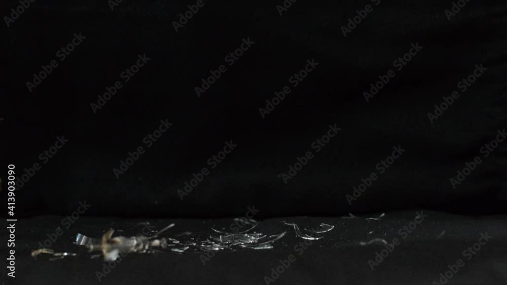 Un martillo golpeando una bombilla y rompiéndola en pedazos sobre fondo negro Un martillo golpeando una bombilla y rompiéndola en pedazos sobre fondo negro
