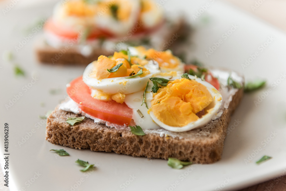 Sliced pumpernickel bread with eggs, tomatoes and sour cream.