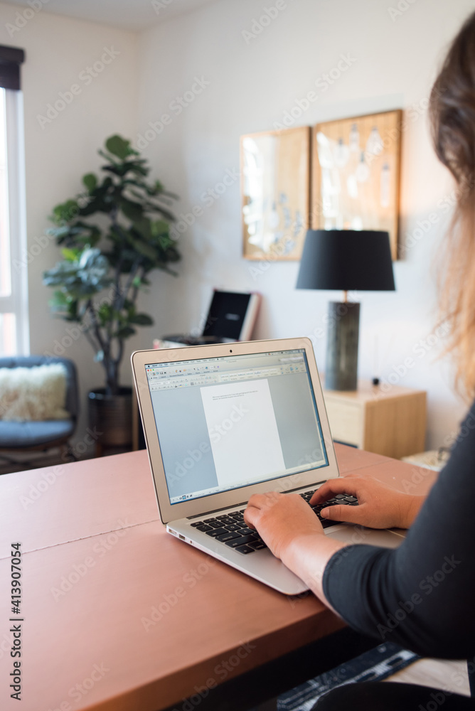 Woman typing on laptop computer in apartment Woman typing on laptop computer in apartment