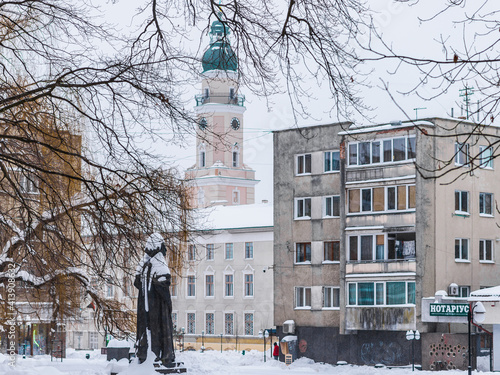 DROHOBYCH, UKRAINE - FEBRUARY 10, 2021: Monument to a Ukrainian philosopher Yuriy Drohobych and the Tower of Drohobych Town Hall. photo